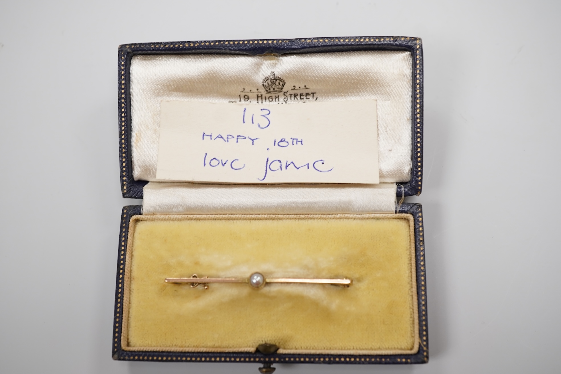 A cased early 20th century 9ct and single stone split pearl set bar brooch, 42mm and a white metal coin bracelet.
